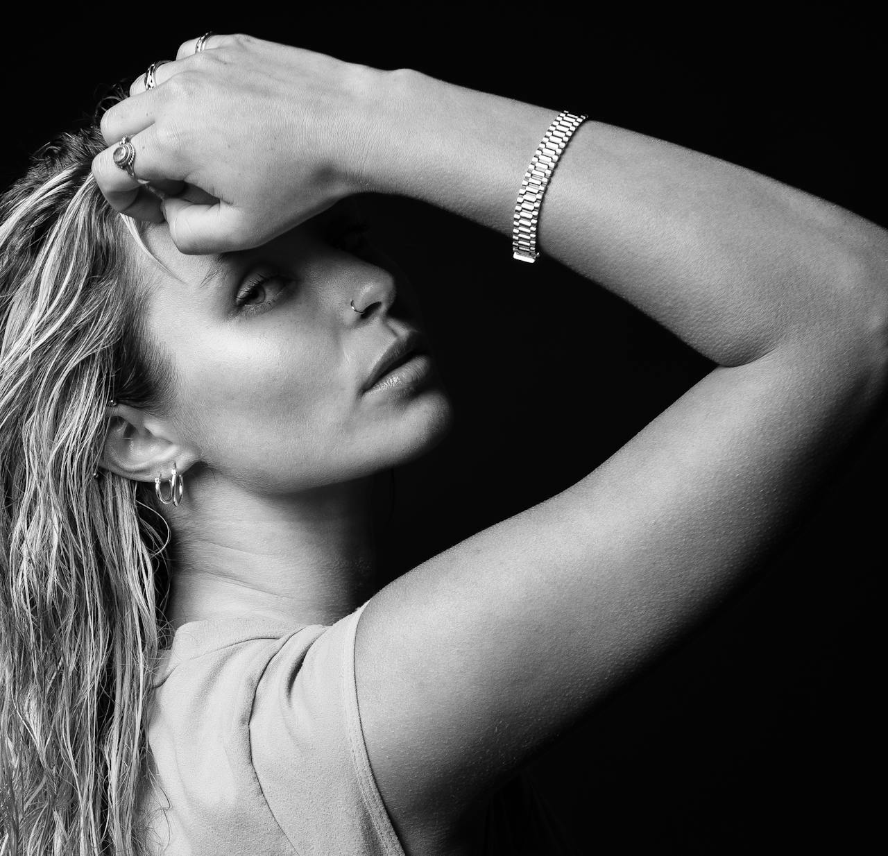 embark Elegant black and white portrait of a woman with arm raised, highlighting jewelry and facial features.